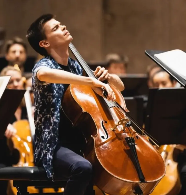 Cellist Krzysztof Michalski performing with an orchestra.